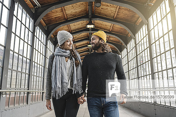 Glückliches junges Paar geht Hand in Hand an einer U-Bahn-Station  Berlin  Deutschland