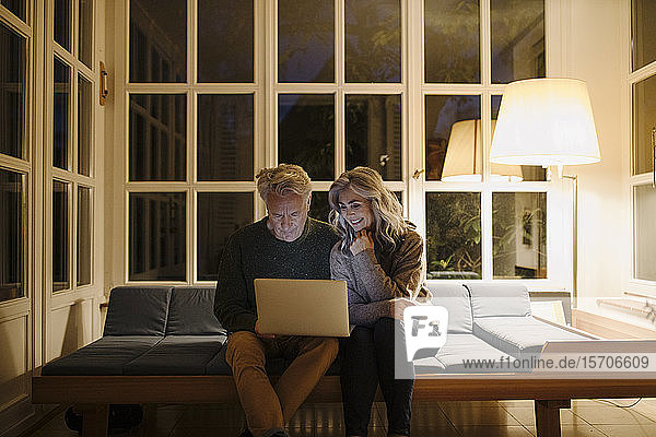 Älteres Ehepaar benutzt abends zu Hause einen Laptop auf der Couch