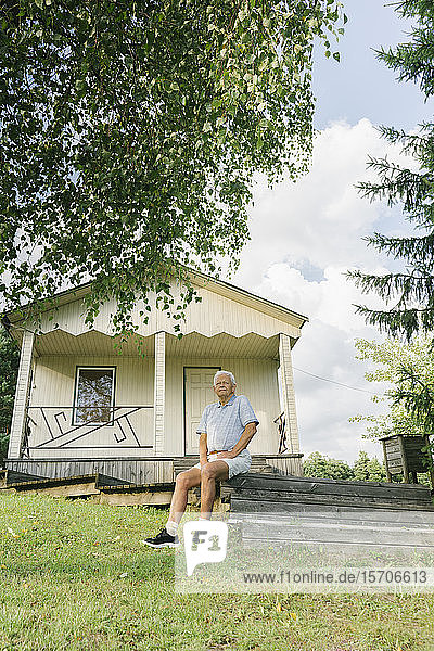 Porträt eines älteren Mannes beim Entspannen vor einem Ferienhaus  Kalvene Lettland