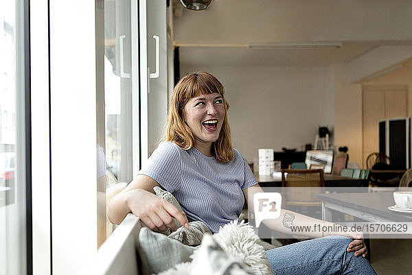 Porträt einer lachenden jungen Frau  die in einem Café sitzt