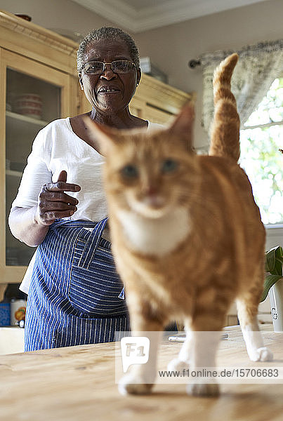 Ältere Frau mit einer Katze in der Küche
