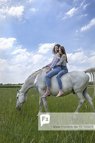 Zwei beste Freunde reiten zusammen auf einem Pferd