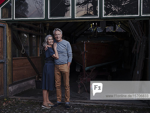 Senior couple standing in front of boathouse