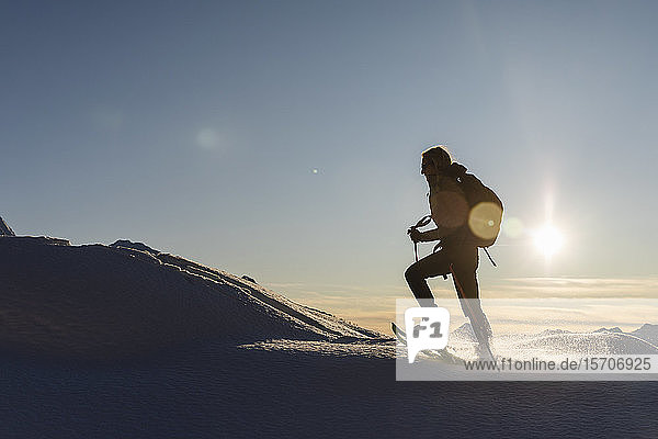 Frau wandert mit Schneeschuhen im Neuschnee in den Bergen bei Sonnenuntergang Valmalenco Italien