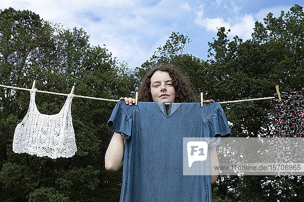 Porträt einer jungen Frau  die hinter einem auf der Wäscheleine trocknenden Kleid steht