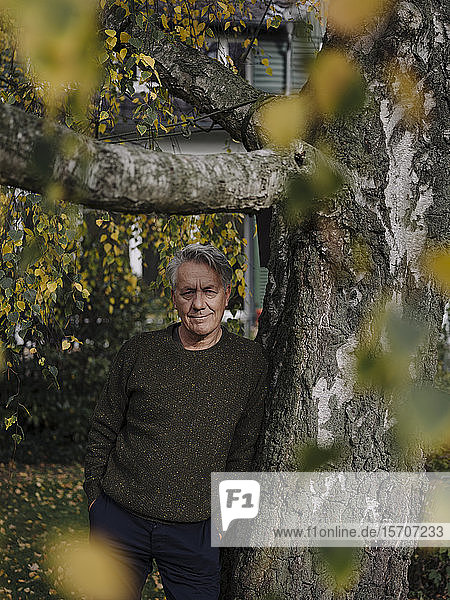 Porträt eines älteren Mannes am Baum im Garten