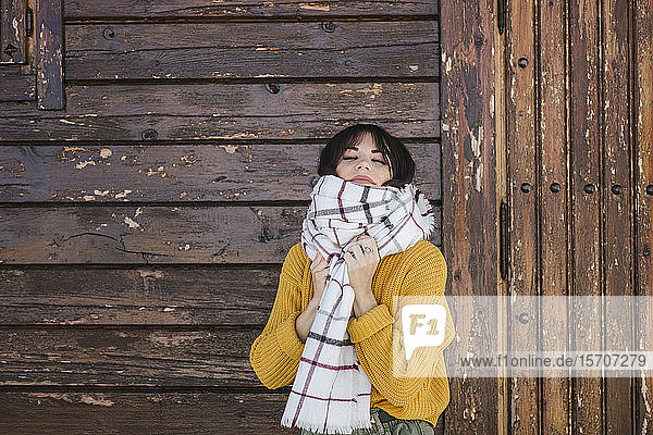 Bildnis einer jungen Frau mit Schal vor einer Holzhütte