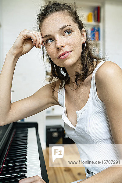 junge Frau  die am Klavier sitzt und lächelt