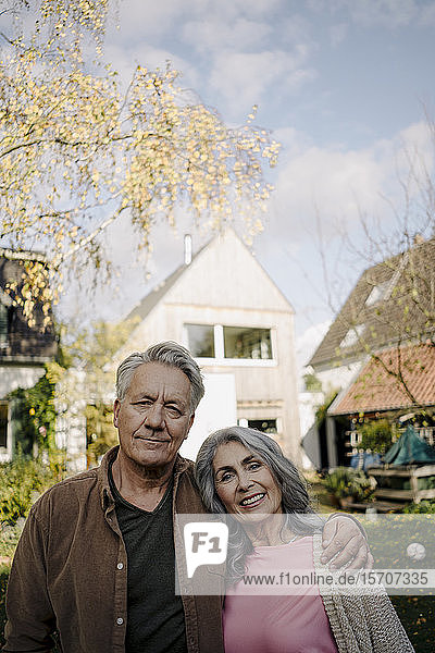 Porträt eines älteren Ehepaares im Garten ihres Hauses im Herbst