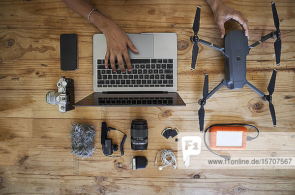 Person sitting at table with photografic equipment using laptop overhead view