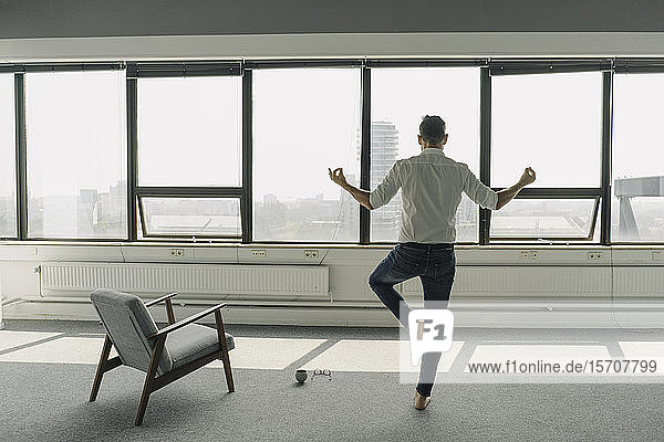 Mature businessman practicing yoga in empty office
