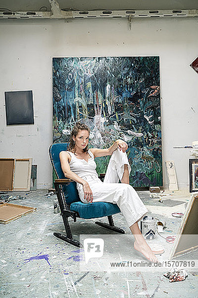 Junge Künstlerin sitzt in ihrem Atelier