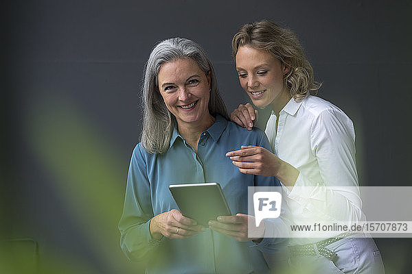 Zwei lächelnde Geschäftsfrauen teilen sich eine Tablette