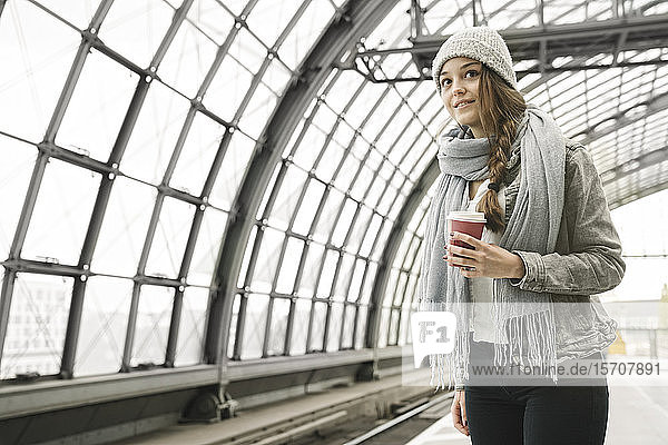 Junge Frau mit Kaffee zum Mitnehmen wartet am Bahnsteig  Berlin  Deutschland