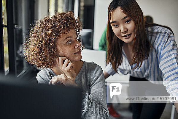 Two businesswomen working together at desk in office