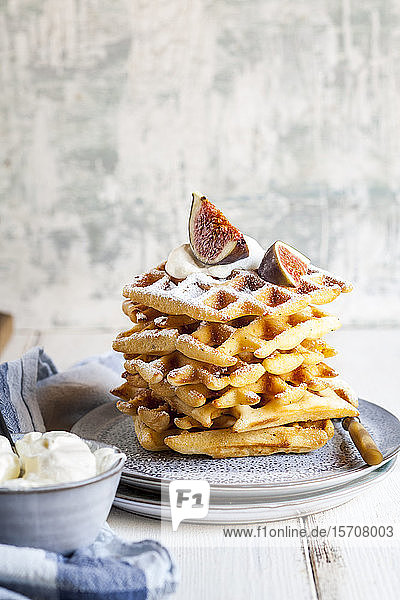 Plate of thick Belgian waffles with whipped cream  powdered sugar and figs