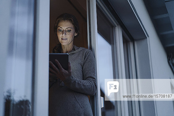 Woman standing in balcony door  using digital tablet