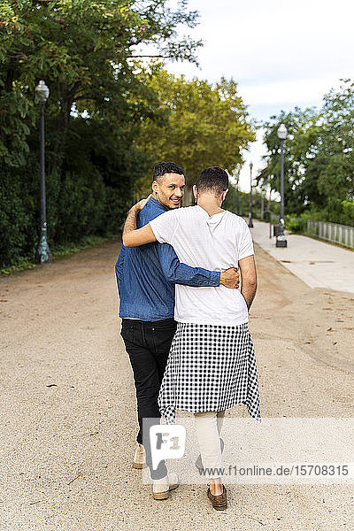 Back view of happy gay couple walking arm in arm in a park  Barcelona  Spain