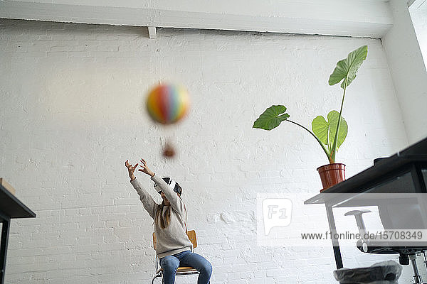 Mädchen mit VR-Brille versucht  im Büro einen Heißluftballon zu fangen