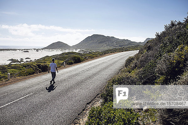 Back view of man walking on country road  Cape Town  Western Cape  South Africa