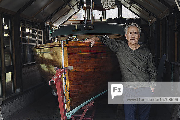 Porträt eines stolzen älteren Mannes auf einem Holzboot in einem Bootshaus