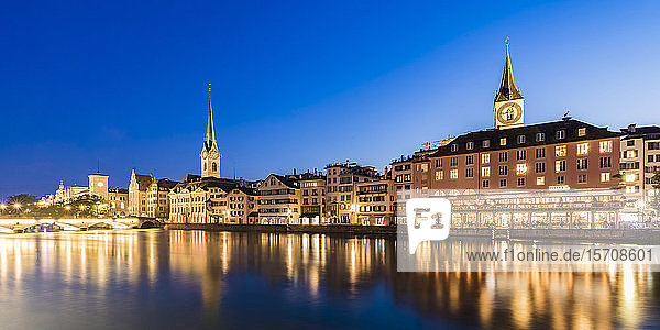 Schweiz  Kanton Zürich  Zürich  Fluss Limmat und Altstadtgebäude entlang der beleuchteten Straße Limmatquai in der Abenddämmerung
