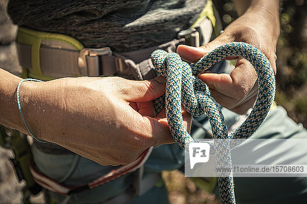 Frau bereitet sich zum Klettern vor  prüft Seil  Achterknoten