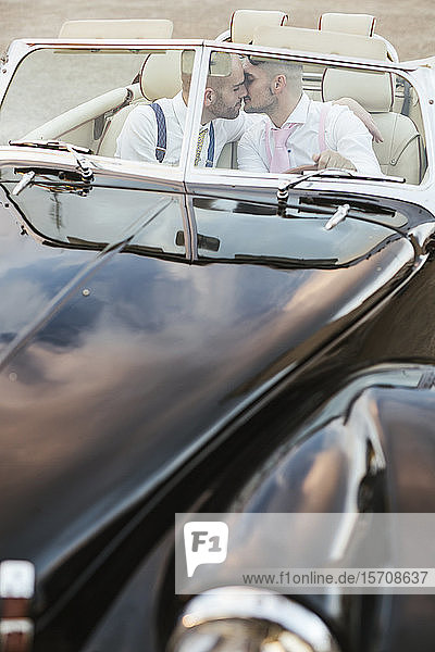 Elegantes schwules Paar küsst sich in einem Oldtimer-Cabriolet