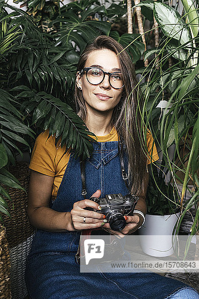 Portrait of a young woman with a camera in a small gardening shop