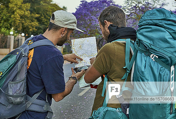 Two backpackers checking a map on a street