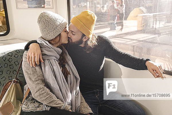 Junges Paar küsst sich in der U-Bahn