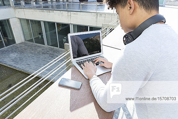 Nahaufnahme eines jungen Mannes mit einem Laptop in der Stadt