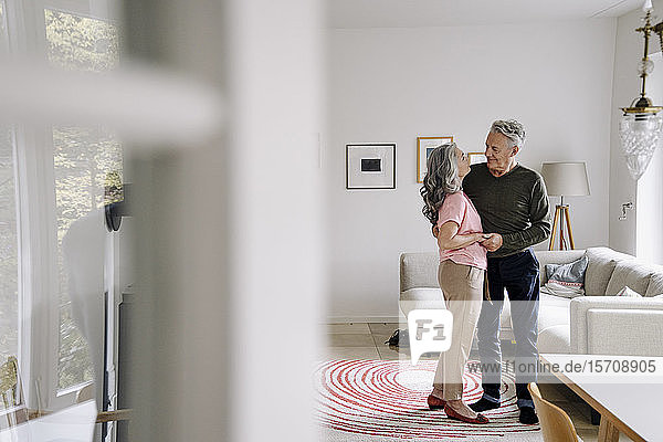 Älteres Ehepaar steht zu Hause im Wohnzimmer