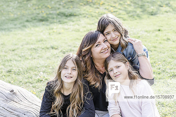 Porträt einer lächelnden Mutter mit drei Drillings-Töchtern auf einer Wiese