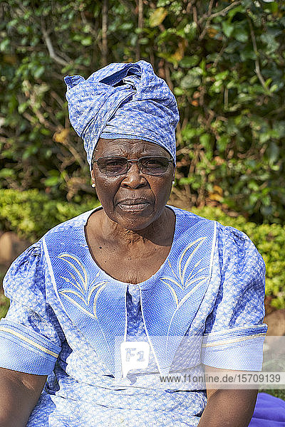Porträt einer älteren Frau mit Kopftuch im Garten