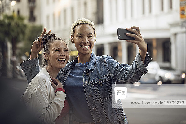 Zwei unbekümmerte junge Frauen  die in der Stadt ein Selfie machen