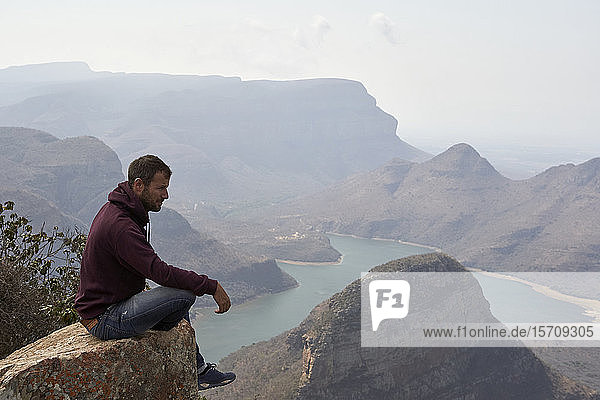 Auf einem Felsen sitzender Mann mit schöner Landschaft als Hintergrund  Blyde River Canyon  Südafrika