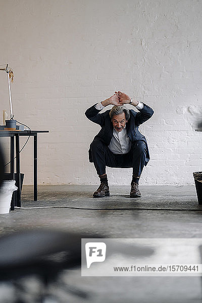 Senior businessman doing gymnastics in office