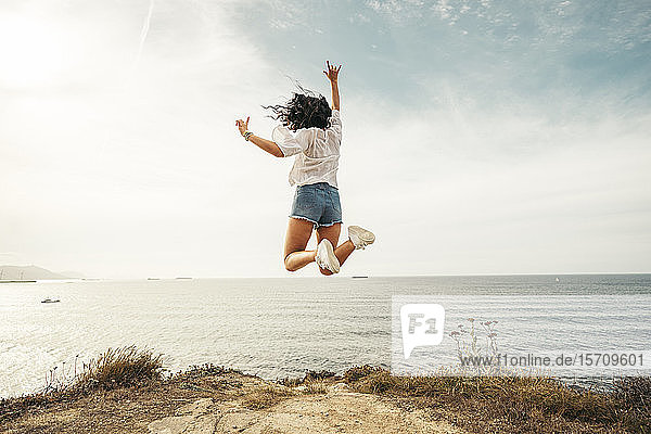 Rückansicht einer jungen Frau  die auf einen Aussichtspunkt springt  Getxo  Spanien