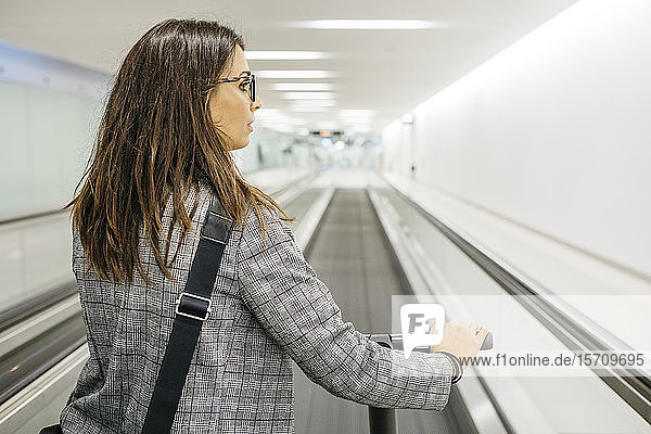 Businesswoman with her electric scooter on moving walkway
