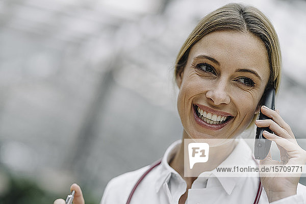 Porträt einer glücklichen Ärztin am Telefon