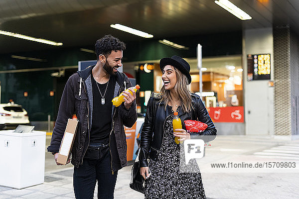 Lachendes junges Paar mit Einkäufen in der Stadt