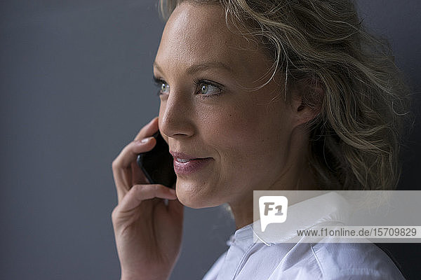 Porträt einer lächelnden jungen Geschäftsfrau am Telefon