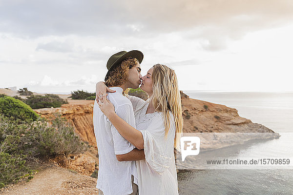 Verliebtes junges Paar küsst sich vor dem Meer  Ibiza  Balearen  Spanien