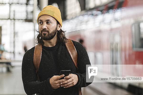 Junger Mann mit Smartphone auf dem Bahnsteig  Berlin  Deutschland