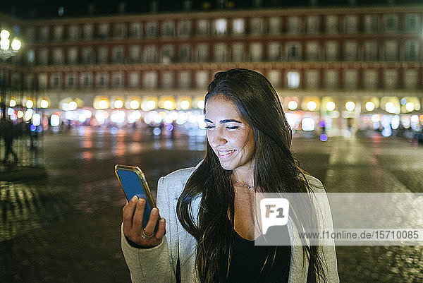 Frau benutzt ihr Smartphone nachts auf der Plaza Mayor  Madrid  Spanien