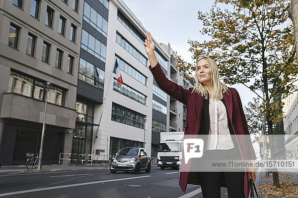 Blond businesswoman in the city hailing a taxi