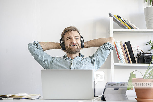 Smiling man listening to music at desk in office