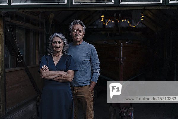 Senior couple standing in front of boathouse