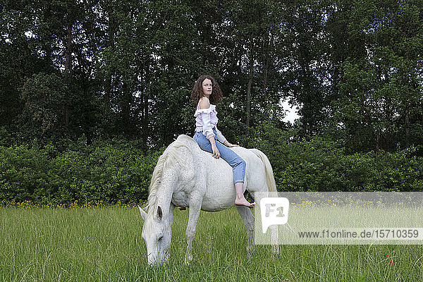 Junge Frau sitzt ohne Sattel auf einem Pferd